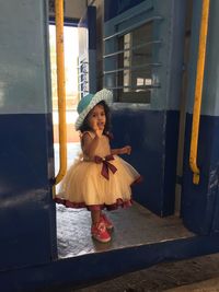 Girl waving while standing at doorway of train