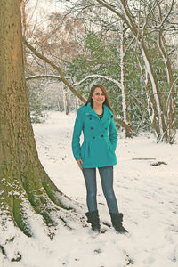 Full length portrait of woman standing on snow covered land