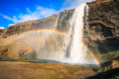 Scenic view of waterfall against sky