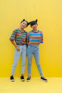 Full length of a smiling young woman against yellow background