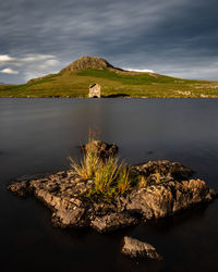 Scenic view of lake by mountain against sky