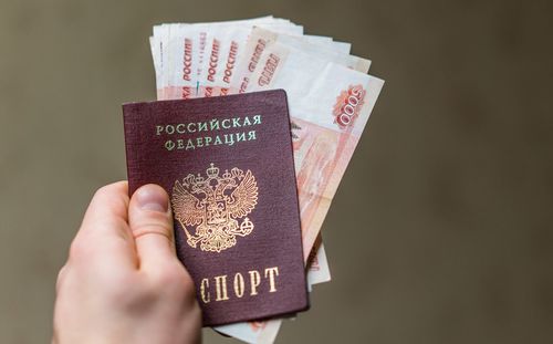 Close-up of man holding money and passport against brown background