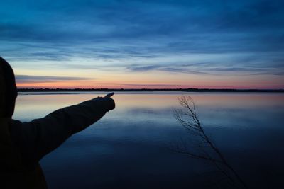 Reflection of silhouette person on lake against sky during sunset
