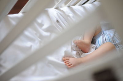 Low section of baby sleeping in crib at home