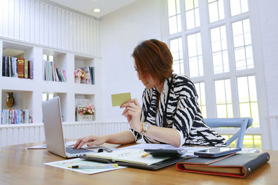 Woman using phone while sitting on table