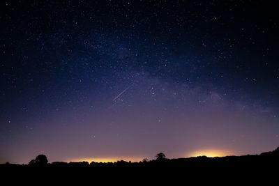 Silhouette landscape against star field at night