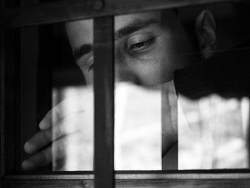 Portrait of young man looking through window