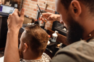 Barber trimming hair of customer