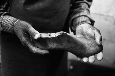 Midsection of shoemaker holding shoe in workshop