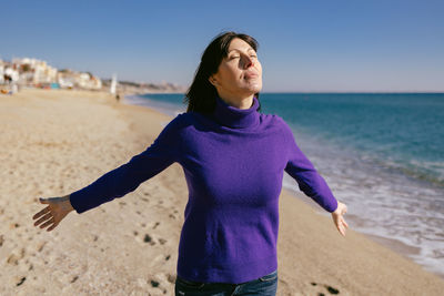 Beautiful mature woman relaxing breathing fresh air on a sunny winter day at the beach