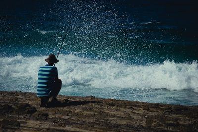 Rear view of man fishing in sea