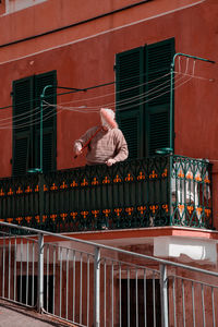 Rear view of man standing by railing against building