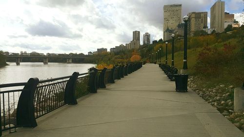 Narrow pathway along river with buildings in background