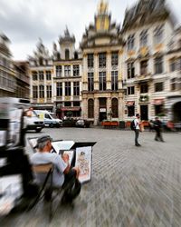 People on street against buildings in city