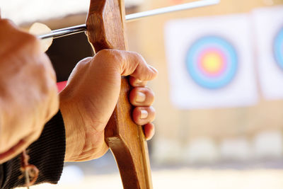 Close-up of man with bow and arrow aiming at target