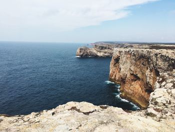 Scenic view of sea by mountains against sky