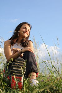 Young woman smiling on field against sky