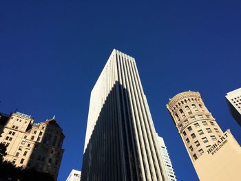 Low angle view of skyscrapers against blue sky