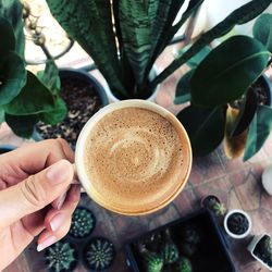 Close-up of hand holding coffee cup on table