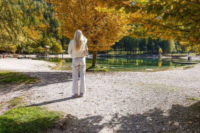 Rear view of woman standing by lake