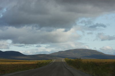 Country road along landscape against sky