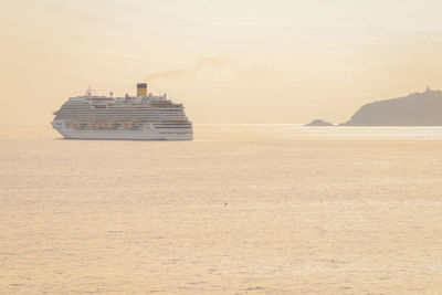 A cruise ship salis near the islands of tino and tinetto, in the golden hour.