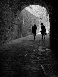 Rear view of people walking in tunnel