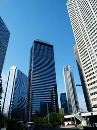 Low angle view of tall buildings against clear blue sky