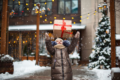 Girl tossing christmas present in air outdoors