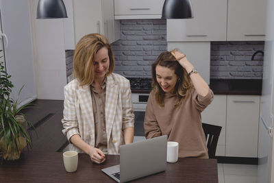 Portrait of smiling woman using digital tablet while sitting at home