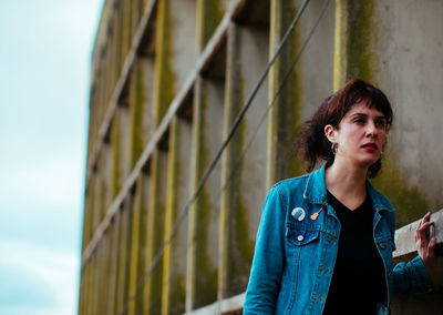 Woman looking away while standing by wall