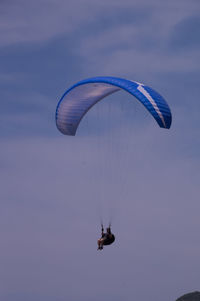 Low angle view of person paragliding against sky