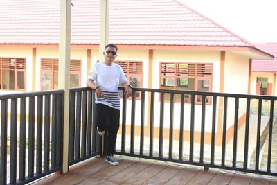 Man standing by railing against building