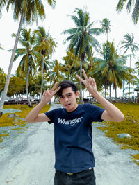 Portrait of teenage boy standing on palm tree