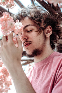 Portrait of young man holding pink flower