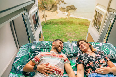 Couple looking at each other lying on the bed of their camper van