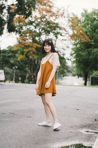 Portrait of a smiling young woman standing on road