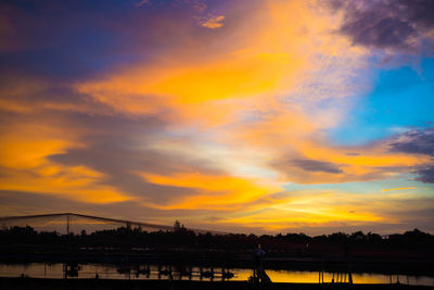 Silhouette bridge over river against sky during sunset