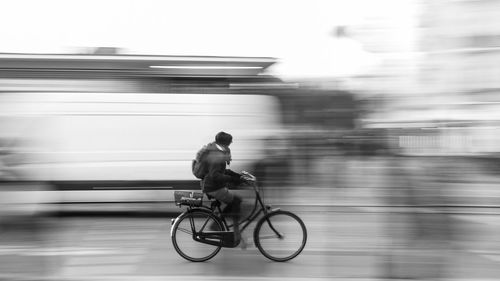 Blurred motion of man riding bicycle on road