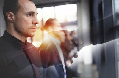 Side view of young man looking through window