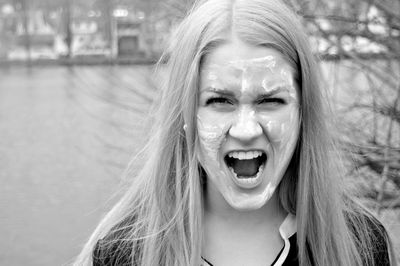 Portrait of angry woman with messy face screaming against lake