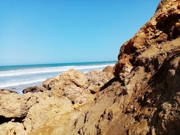 Rock formation on beach against clear blue sky
