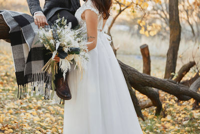 Midsection of bride holding bouquet