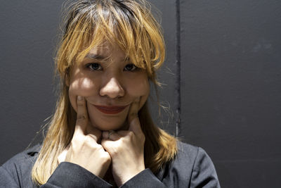 Close-up portrait of smiling businesswoman against wall