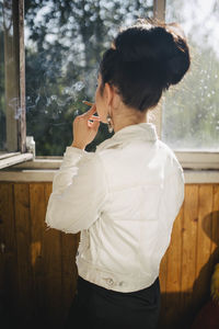 Smoking woman on the balcony standing with her back