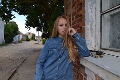 Portrait of woman with hand on chin leaning on wall