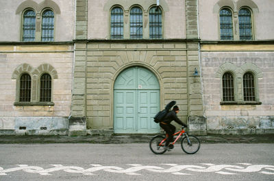 Side view of man riding bicycle against building