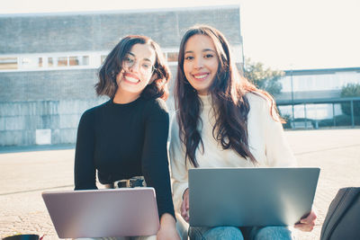 Portrait of businesswomen with laptops on sunny day