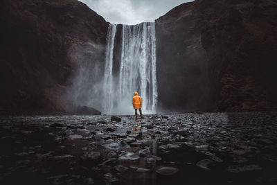 Rear view of man looking at waterfall