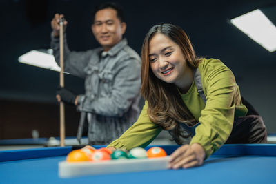 Portrait of young woman playing pool
